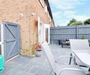 a patio with two white chairs and a door at Recently renovated,modern house. train station in North Mimms