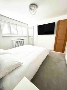 a bedroom with a large white bed and a flat screen tv at Recently renovated,modern house. train station in North Mimms