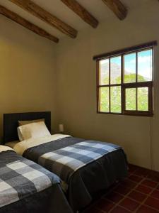 two beds in a room with a window at Bungalow Lamay - Cusco in Lamay