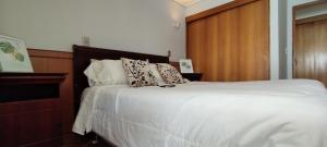 um quarto com uma cama com lençóis brancos e almofadas em Depto Concón frente a playa amarilla con gran vista al mar em Concón