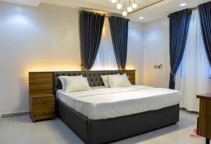 una camera da letto con un grande letto con tende blu di 99 MOZILLA APARTMENTS AND SUITES ad Abuja