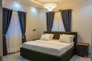 um quarto com uma cama grande e cortinas azuis em 99 MOZILLA APARTMENTS AND SUITES em Abuja