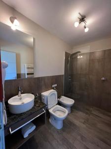 ein Badezimmer mit 2 WCs, einem Waschbecken und einem Spiegel in der Unterkunft Tandil del Lago in Tandil