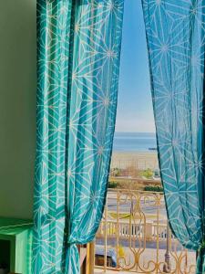 - une fenêtre avec vue sur la plage et l'océan dans l'établissement Alloggio in palazzina stile Liberty Fronte Mare, à Nettuno