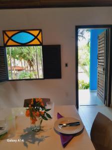 een eetkamer met een tafel en een raam bij Caçadores de Aventuras Flats in Pipa