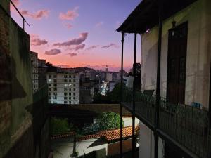 a view of a city at sunset from a balcony at Guattari House Santa Teresa in Rio de Janeiro