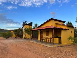 une petite maison jaune avec une table et des chaises dans l'établissement Casa Barreirinho Parque Nacional Serra da Capivara, à Coronel José Diaz