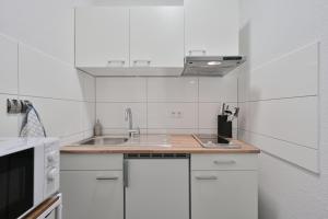 a white kitchen with a sink and a microwave at Goodliving Apartments Studio mit Balkon & Netflix in Essen