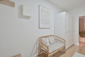 ein weißes Zimmer mit einem Rattanstuhl an der Wand in der Unterkunft Goodliving Apartments Studio mit Balkon & Netflix in Essen