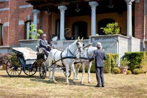 two men standing next to a horse drawn carriage at B&B Villa Cernigliaro Dimora Storica in Sordevolo