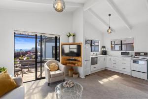 a kitchen with white cabinets and a tv in a room at Beverley Hills Guesthouse in Whangamata