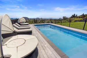 uma piscina com duas espreguiçadeiras ao lado em Beverley Hills Guesthouse em Whangamata