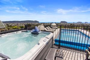 a hot tub on a balcony next to a swimming pool at Beverley Hills Guesthouse in Whangamata