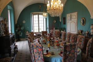 ein Esszimmer mit einem Tisch, Stühlen und einem Kronleuchter in der Unterkunft Abbaye de Reigny - Esprit de France in Vermenton