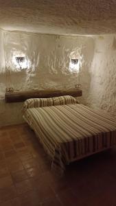 Cama pequeña en habitación con 2 ventanas en La Cueva Colosal, en Alcalá del Júcar