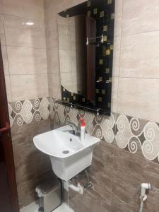 uma casa de banho com um lavatório branco e um espelho. em اجنحة أروى سويتس الدمام Arwa Suites Dammam em Dammam
