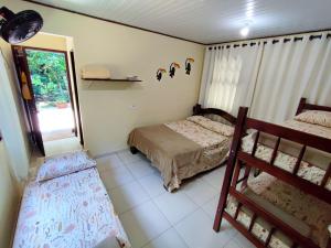 1 dormitorio con 2 camas y ventana en Chalé da cachoeira - Ilhabela, en Ilhabela