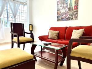 a living room with a red couch and two chairs at Apartamento Cerca Al centro in Valledupar