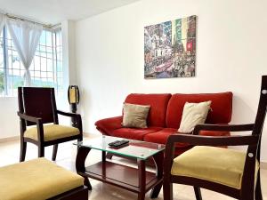 uma sala de estar com um sofá vermelho e duas cadeiras em Apartamento Cerca Al centro em Valledupar