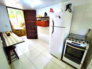 a kitchen with a white refrigerator and a stove at Chalé da cachoeira - Ilhabela in Ilhabela