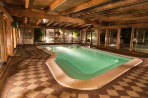 a swimming pool in a house with a wooden ceiling at Hotel Ricordo Du Parc in Tabiano