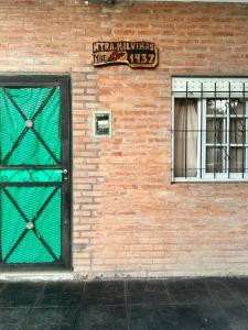 - un bâtiment en briques avec une porte verte et une fenêtre dans l'établissement Alojamiento Mia, à Monte Grande