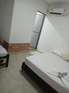 een slaapkamer met een wit bed en een raam bij Mónaco habitaciones in Coveñas