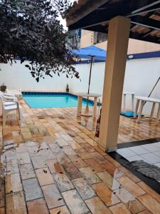 un patio con mesa, sombrilla y piscina en VILLAGE PÉ NA AREIA en Salvador