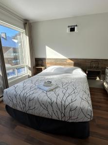 a large bed in a bedroom with a large window at Auberge Morritt in Mont-Tremblant