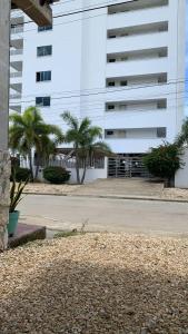 a large white building with palm trees in front of it at Mónaco habitaciones in Coveñas