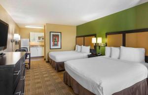 a hotel room with two beds and a flat screen tv at Extended Stay America Select Suites - Raleigh - RDU Airport in Morrisville