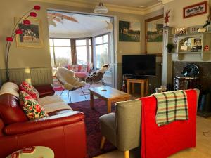 a living room with a couch and a tv at Cowden Farmhouse, near Stonehaven. in Glenbervie