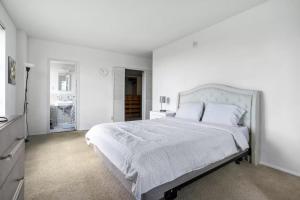 a white bedroom with a large bed with white sheets and pillows at Spacious 2 Bedroom 2 Bathroom Unit Great Location in Los Angeles