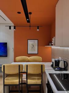eine Küche mit orangefarbenen Wänden und einem Tisch mit Stühlen in der Unterkunft Luxurious Dreamy seaside apartment in Durrës