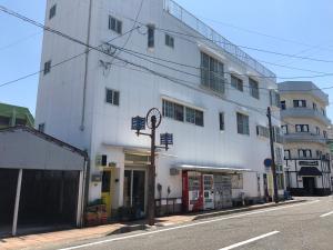 um edifício branco ao lado de uma rua em ゲストハウス奄美ルリカケス em Amami