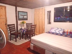 1 dormitorio con 1 cama, mesa y sillas en Thornton's Sea View Cafe & Guesthouse en Siquijor