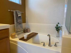 a white bath tub with a wooden tray in a bathroom at Spacious & Sunny South Reno Home, Near Trails & Shopping 3 beds in Steamboat