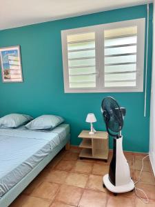 - une chambre bleue avec un lit et un ventilateur dans l'établissement La Yole - appartement, à Bois-Neuf