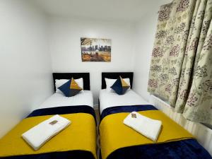 two beds in a room with yellow and blue at Tower Bridge London, 2 Bedrooms, Reception, Kitchen, Parking in London