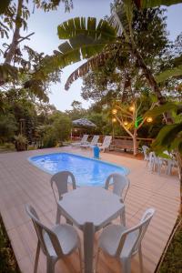 eine Terrasse mit einem Tisch und Stühlen neben einem Pool in der Unterkunft Aruana Suites Tranquilidade e Sossego no meio da Natureza a 5km da Vila de Praia do forte in Praia do Forte