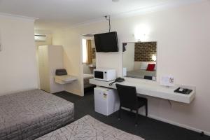 a hotel room with a bed and a desk with a computer at Top of the Town Motel in Inverell