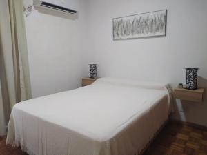 een wit bed in een witte kamer met een raam bij La Victoria in Rosario