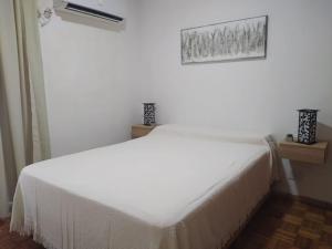 a white bed in a white room with a window at La Victoria in Rosario