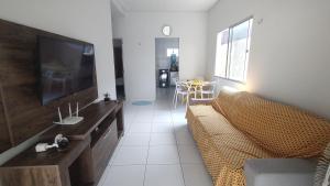 a living room with a couch and a flat screen tv at Casa Caminho da Alvorada in Parnaíba