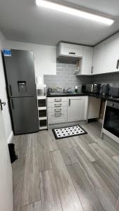 kuchnia z lodówką ze stali nierdzewnej i drewnianą podłogą w obiekcie London charming bedroom flat w Londynie