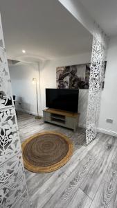 a living room with a flat screen tv and a rug at London charming bedroom flat in London