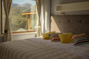 a bedroom with a bed with pillows and a window at Villa de los Ñires in Ushuaia