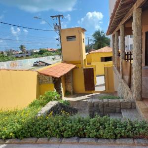 uma casa amarela com uma piscina em frente em Pousada Encontro das águas em Fortaleza