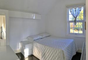 a white bedroom with a bed and a window at Idyllic Cottage in Jubilee Park in London