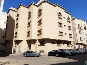 a large building with cars parked in front of it at Qurban Apartment in Al ‘Awālī